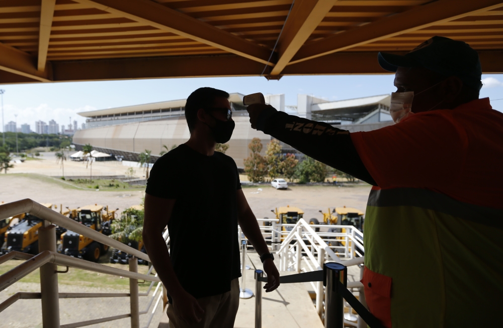 Soccer Football - Copa America 2021 - A worker at the stadium checks the temperature of another worker, before they are allowed to enter REUTERS/Mariana Greif 