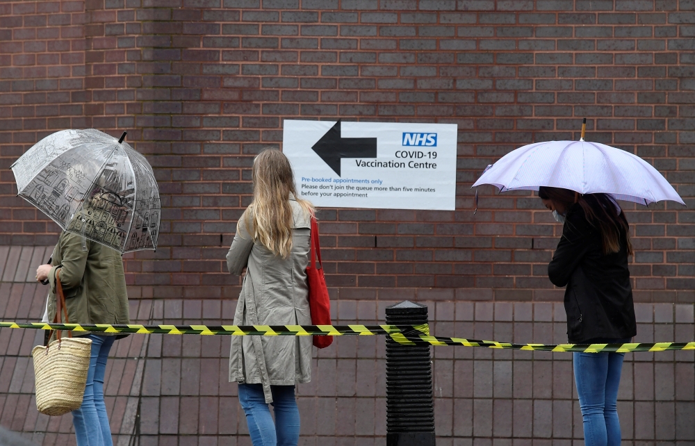 People queue in the rain to receive a COVID-19 vaccination amid the spread of the coronavirus disease pandemic, London, Britain, June 18, 2021. Reuters/Toby Melville
