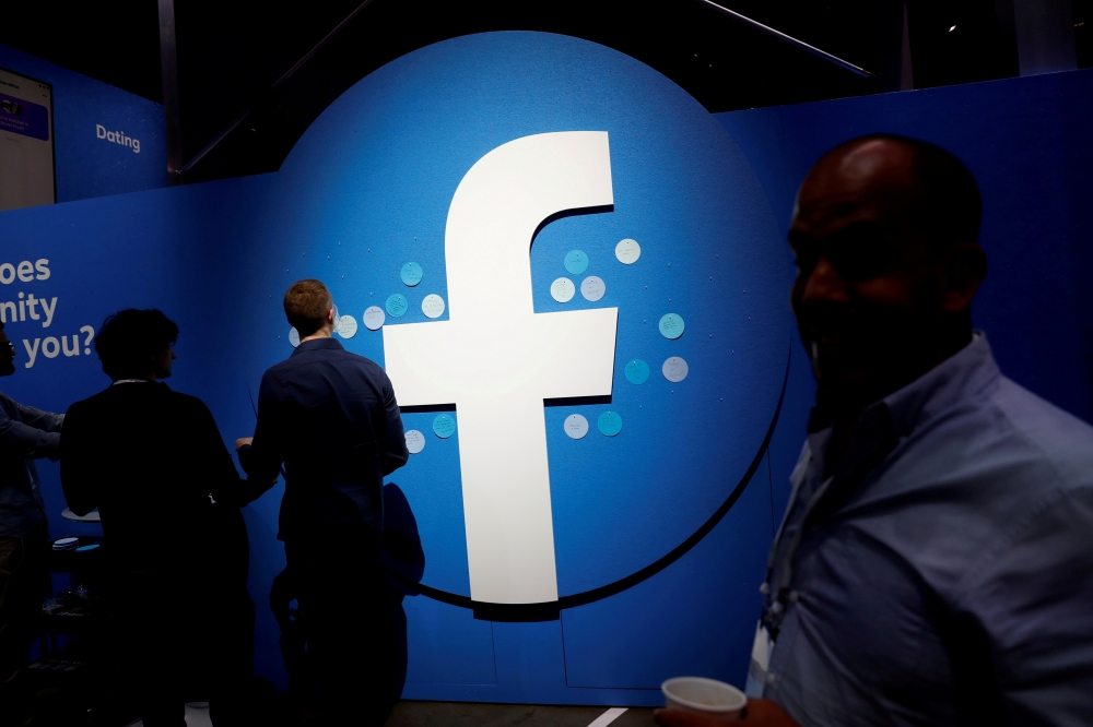 Attendees walk past a Facebook logo during Facebook Inc's F8 developers conference in San Jose, California, U.S., April 30, 2019. Reuters/Stephen Lam/File Photo