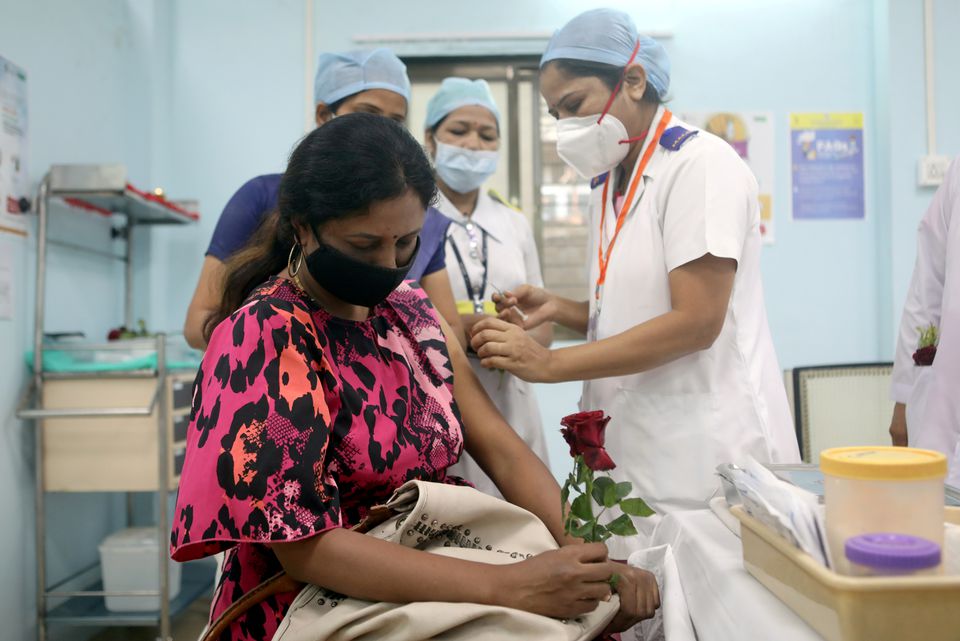 A healthcare worker holding a rose receives an AstraZeneca's COVISHIELD vaccine, during the coronavirus disease (COVID-19) vaccination campaign, at a medical centre in Mumbai, India, January 16, 2021. REUTERS/Francis Mascarenhas/File Photo
