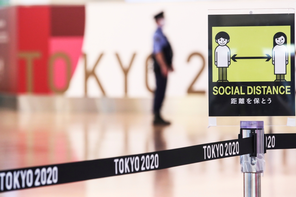 A social distancing sign is seen in front of a police officer before the arrival of International Olympic Committee (IOC) President Thomas Bach at Haneda Airport ahead of Tokyo 2020 Olympic Games, in Tokyo, Japan July 8, 2021. REUTERS/Kim Kyung-Hoon