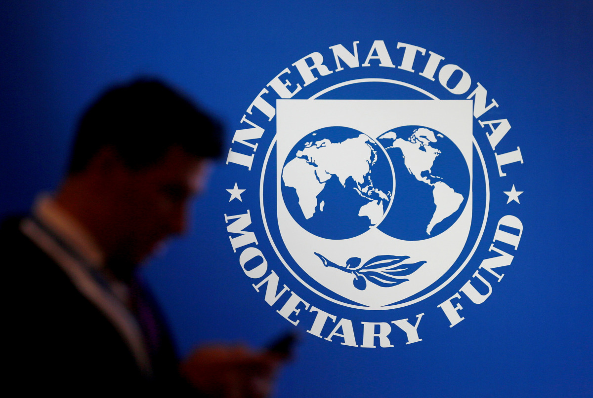 A man stands near a logo of International Monetary Fund. (Reuters/File Photo)