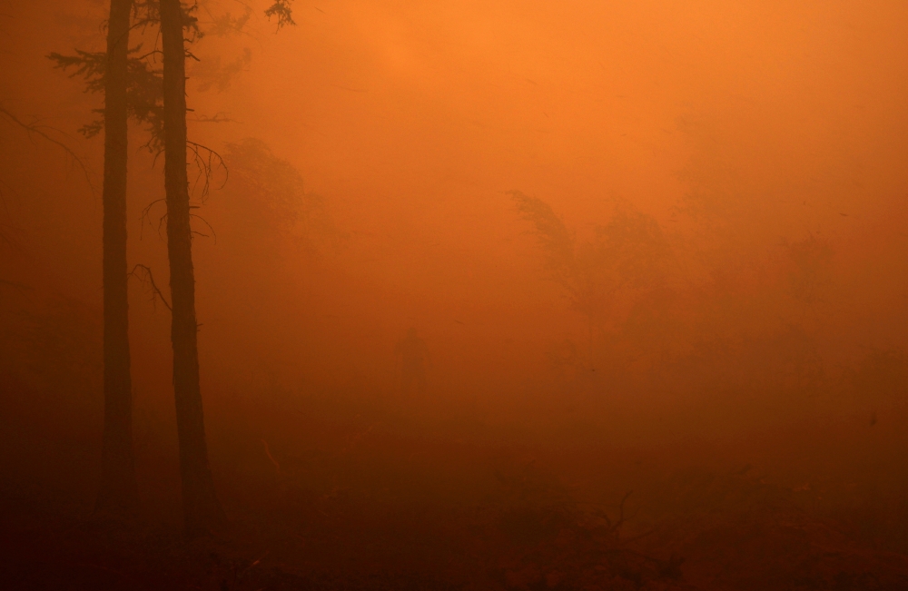 A firefighter works to extinguish a forest fire near the village of Magaras in the region of Yakutia, Russia July 17, 2021. REUTERS/Roman Kutukov/File Photo