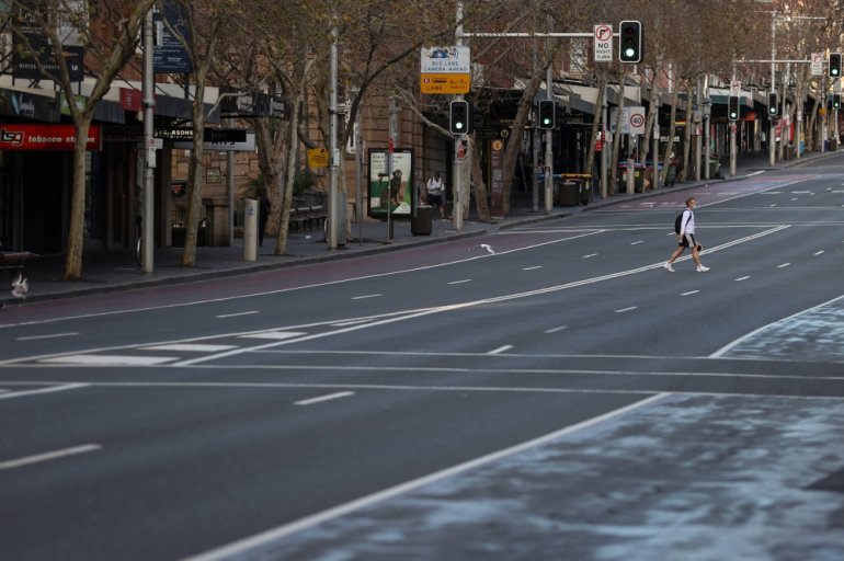 A lone man wearing a protective face mask crosses an empty street during a lockdown to curb the spread of a coronavirus disease (COVID-19) outbreak in Sydney, Australia, July 22, 2021. REUTERS/Loren Elliott

