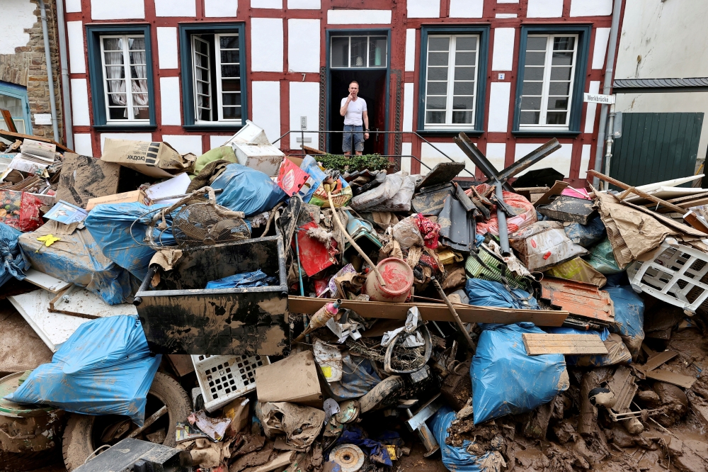 A man looks on outside a house in an area affected by floods caused by heavy rainfalls in Bad Muenstereifel, Germany, July 19, 2021. REUTERS/Wolfgang Rattay/File Photo