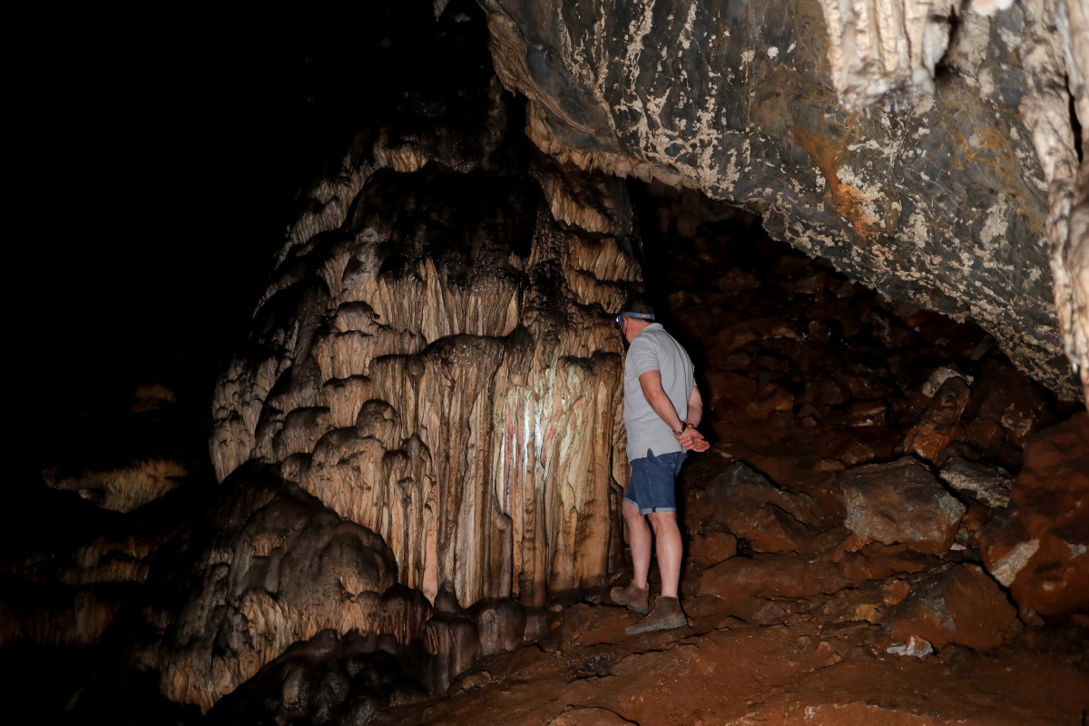 A guide looks at red ocher markings which were painted on stalagmites by Neanderthals about 65,000 years ago, according to an international study, in a prehistoric cave in Ardales, southern Spain, August 7, 2021. Picture taken August 7, 2021. REUTERS/Jon 