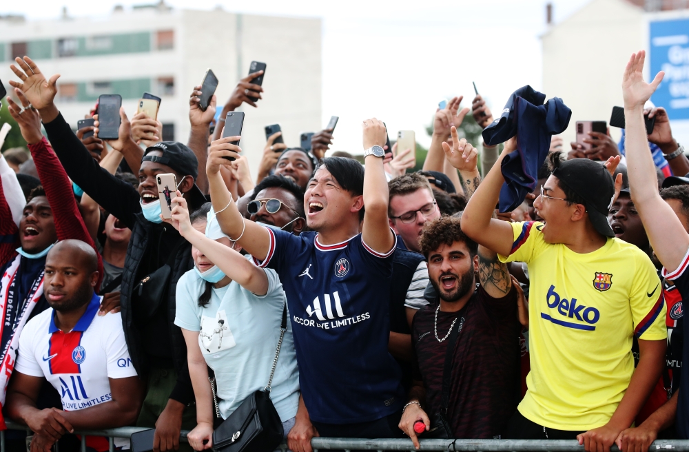 August 10, 2021 Paris St Germain fans celebrate as they await the arrival of Lionel Messi outside Paris-Le Bourget airport REUTERS/Yves Herman