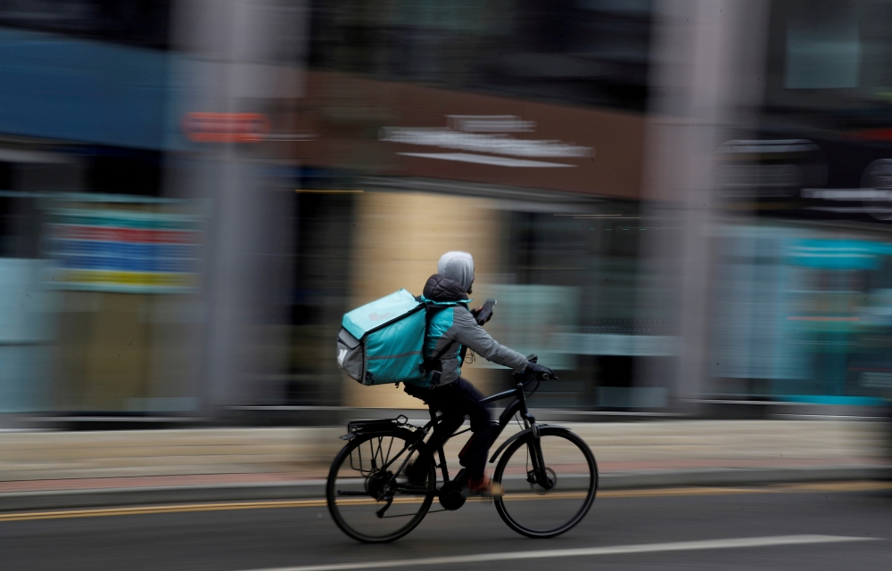 A Deliveroo delivery driver cycles through the centre of Manchester, Britain, March 8, 2021. REUTERS/Phil Noble/File Photo/File Photo