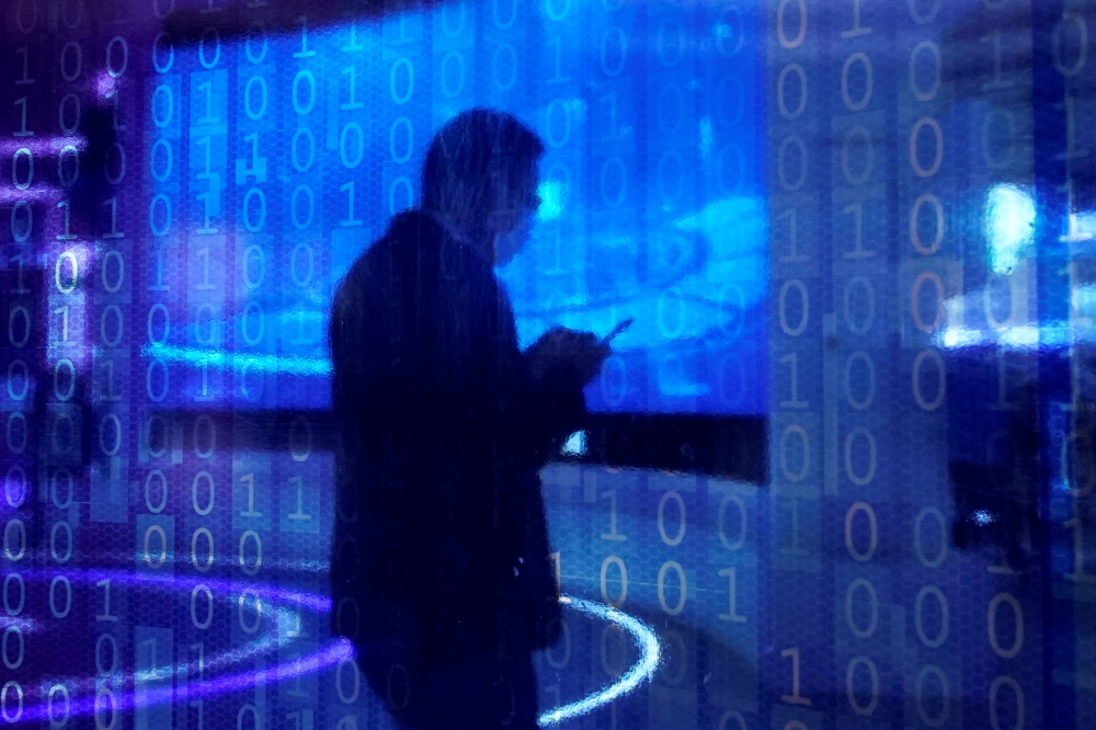 A man looking at a phone is seen through a digitally decorated glass during the World Internet Conference (WIC) in Wuzhen, Zhejiang province, China, November 23, 2020. REUTERS/Aly Song/File Photo