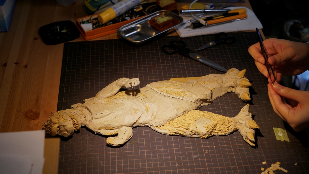 A cardboard sculpture of Godzilla is seen on the desk of 29-year-old artist Monami Ohno in Tokyo, Japan August 25, 2021. Picture taken August 25, 2021. REUTERS/Joseph Campbell