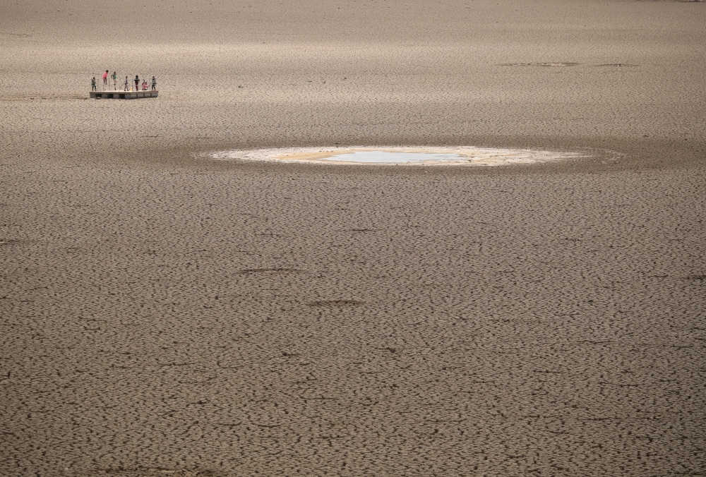 Children play as caked clay is seen in the dried up municipal dam in drought-stricken Graaff-Reinet, South Africa, November 17, 2019. Picture taken November 17, 2019. REUTERS/Mike Hutchings/File Photo