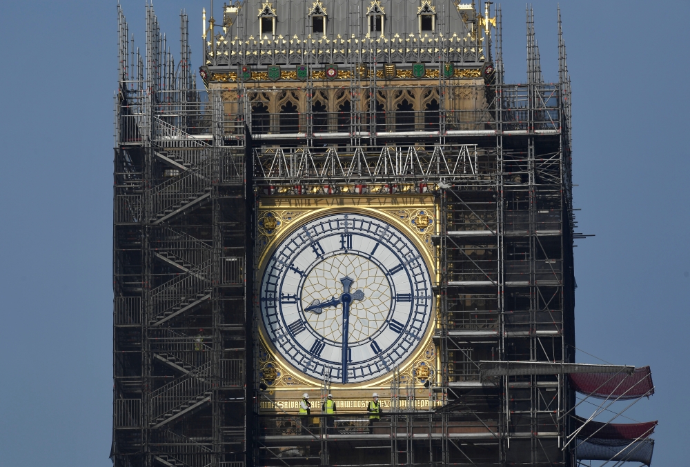 Workers stand on scaffolding underneath one of the clock faces on the Elizabeth Tower, more commonly known as Big Ben, as hands and dials are seen restored to the original Prussian blue colouring, whilst renovation works continue at the Houses of Parliame