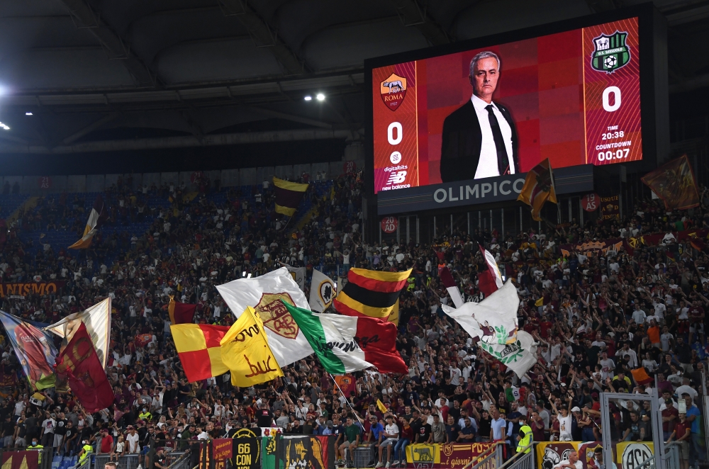 Roma fans wave flags as a picture of AS Roma coach Jose Mourinho is displayed on the big screen before the match REUTERS/Alberto Lingria