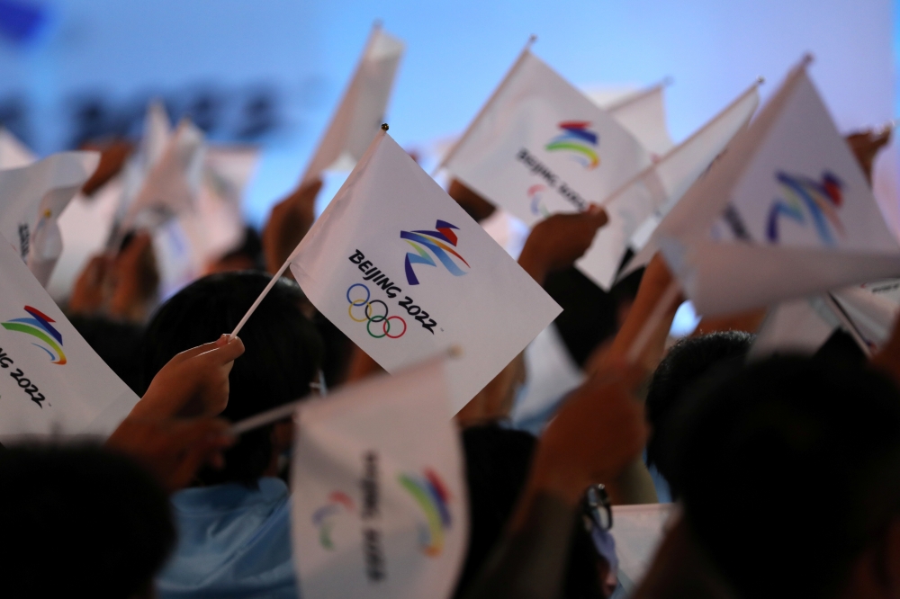 Attendees wave flags with the emblem of the Beijing 2022 Winter Olympic Games at a ceremony unveiling the slogan, in Beijing, China September 17, 2021. REUTERS/Tingshu Wang

