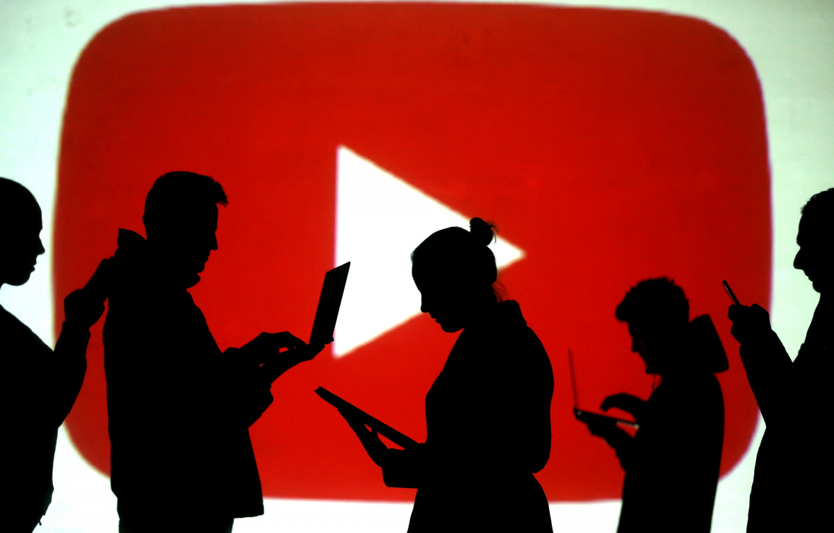 FILE PHOTO: FILE PHOTO: Silhouettes of laptop and mobile device users are seen next to a screen projection of the YouTube logo in this picture illustration taken March 28, 2018. REUTERS/Dado Ruvic/Illustration/File Photo/File Photo
