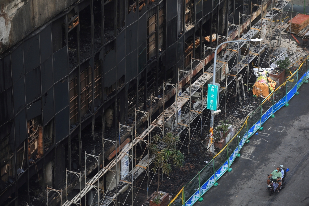 People ride on a vehicle past a damaged residential building following a fire in Kaohsiung, Taiwan October 15, 2021. REUTERS/I-Hwa Cheng TPX IMAGES OF THE DAY