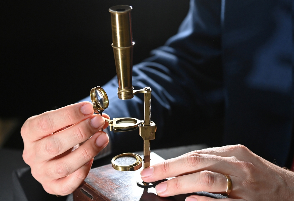 James Hyslop, Head of Scientific Instruments, Globes and Natural History at Christie's, demonstrates the Darwin Family Microscope, owned and used by the English naturalist and founder of the concept of evolution, Charles Darwin, which will be offered at a