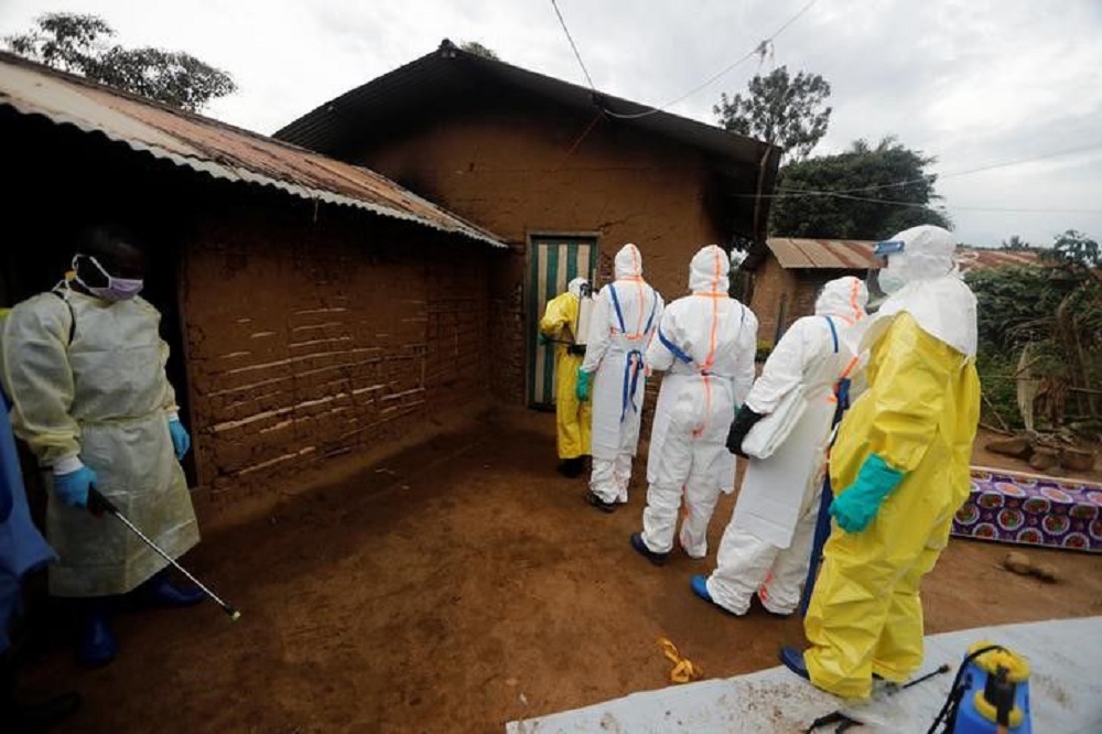 A healthcare worker who volunteered in the Ebola response, stands with decontamination gear as his colleague prepare to enter a house where a woman, is suspected of dying of Ebola in the Eastern Congolese town of Beni in the Democratic Republic of Congo, 