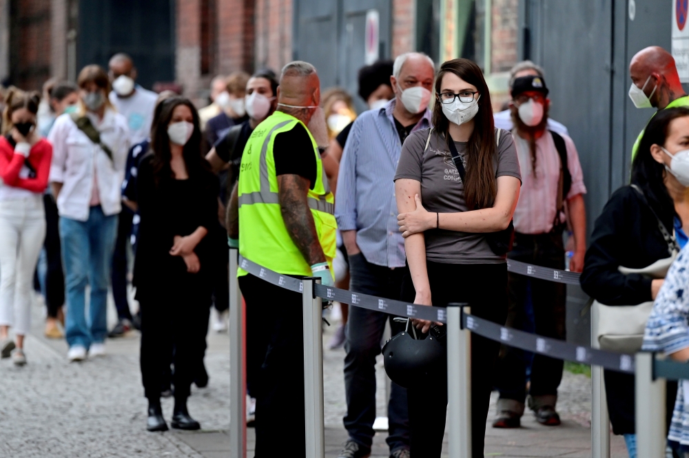 People queue to receive a vaccine against the coronavirus disease (COVID-19), during a night of vaccinations with music, at the Arena Treptow vaccination centre in Berlin, Germany, August 9, 2021. John Macdougall/Pool via REUTERS/File Photo