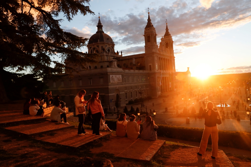 Tourists and locals watch the sunset by La Almudena Cathedral in Madrid, Spain, October 3, 2021. REUTERS/Susana Vera/File Photo