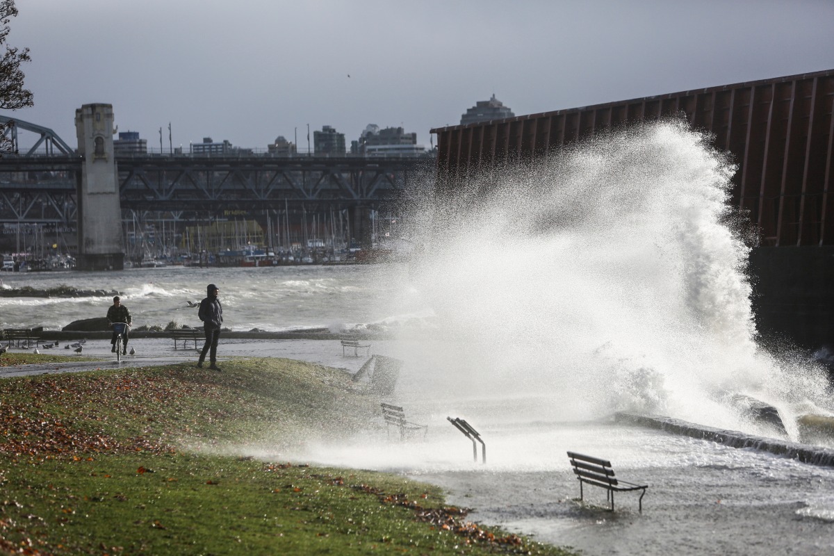 A man watches waves crash ashore where a barge that came loose from its mooring collided with the sea wall after rainstorms lashed the western Canadian province of British Columbia in Vancouver, British Columbia, Canada November 15, 2021. REUTERS/Jesse Winter
