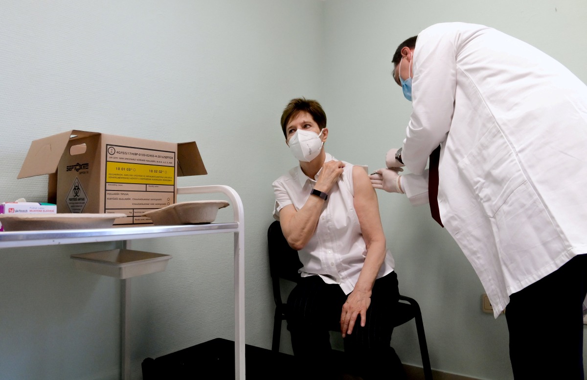 FILE PHOTO: Healthcare worker Adrienne Kertesz receives a dose of the Pfizer-BioNTech COVID-19 vaccine at the Del-Pest Central Hospital as the coronavirus disease (COVID-19) outbreak continues, in Budapest, Hungary, December 26, 2020. Szilard Koszticsak/Pool via REUTERS/File Photo
