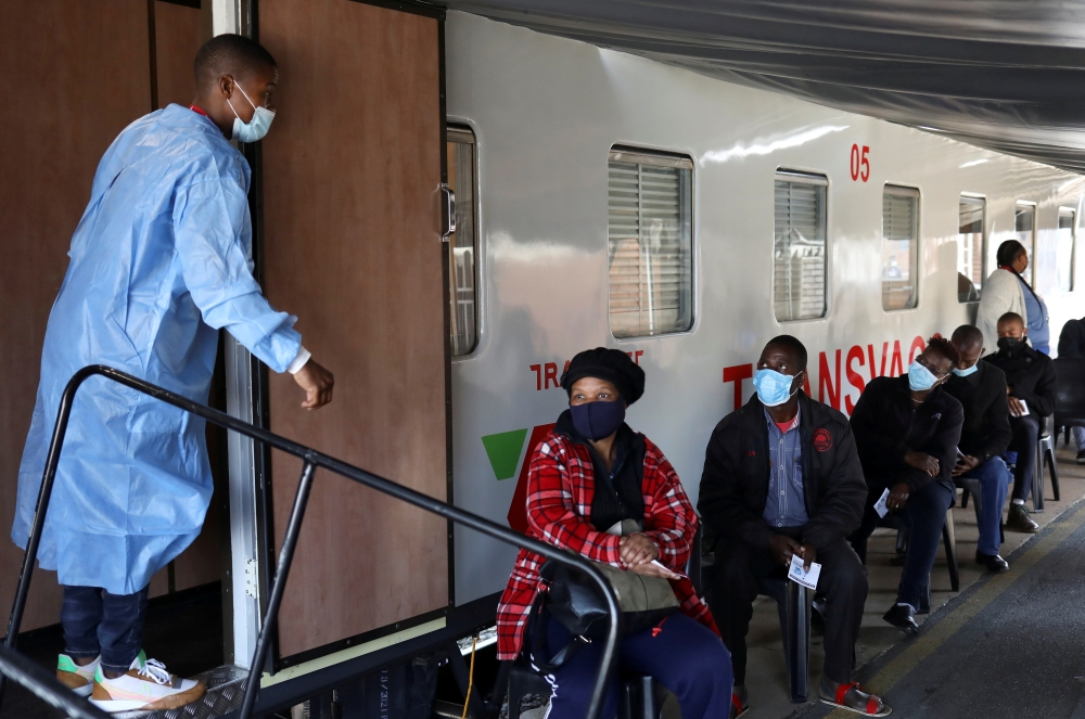 A health worker talks to people as they wait to register next to the Transvaco coronavirus disease (COVID-19) vaccine train, after South Africa's rail company Transnet turned the train into a COVID-19 vaccination center on rails to help the government speed up its vaccine rollout in the country's remote communities, at the Springs train station on the East Rand, South Africa, August 30, 2021. REUTERS/Siphiwe Sibeko/File Photo