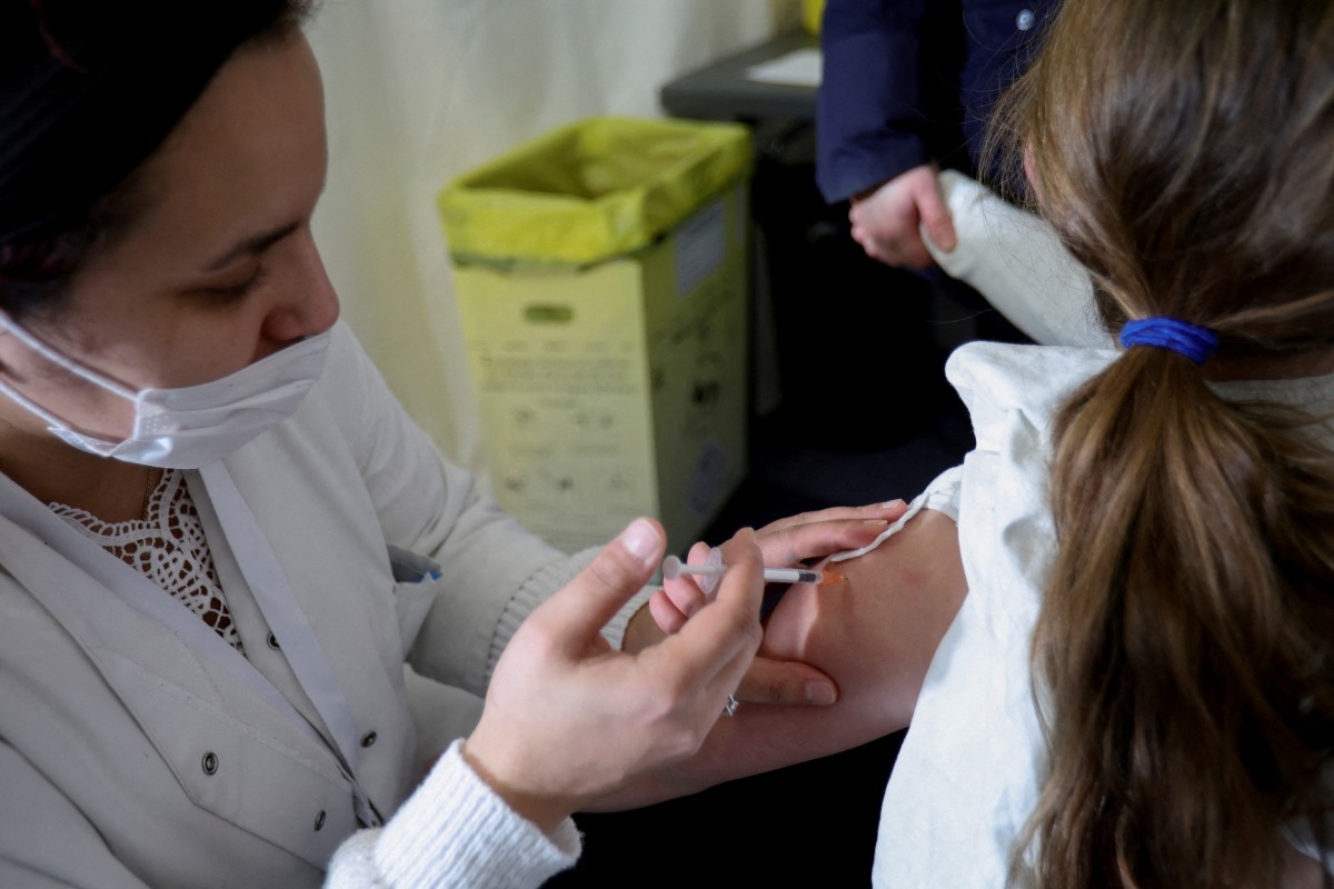 FILE PHOTO: A medical worker administers a dose of a coronavirus disease (COVID-19) vaccine to a child at a vaccination centre in Les Pavillons-sous-Bois, near Paris, France, December 18, 2021. REUTERS/Sarah Meyssonnier/File Photo
