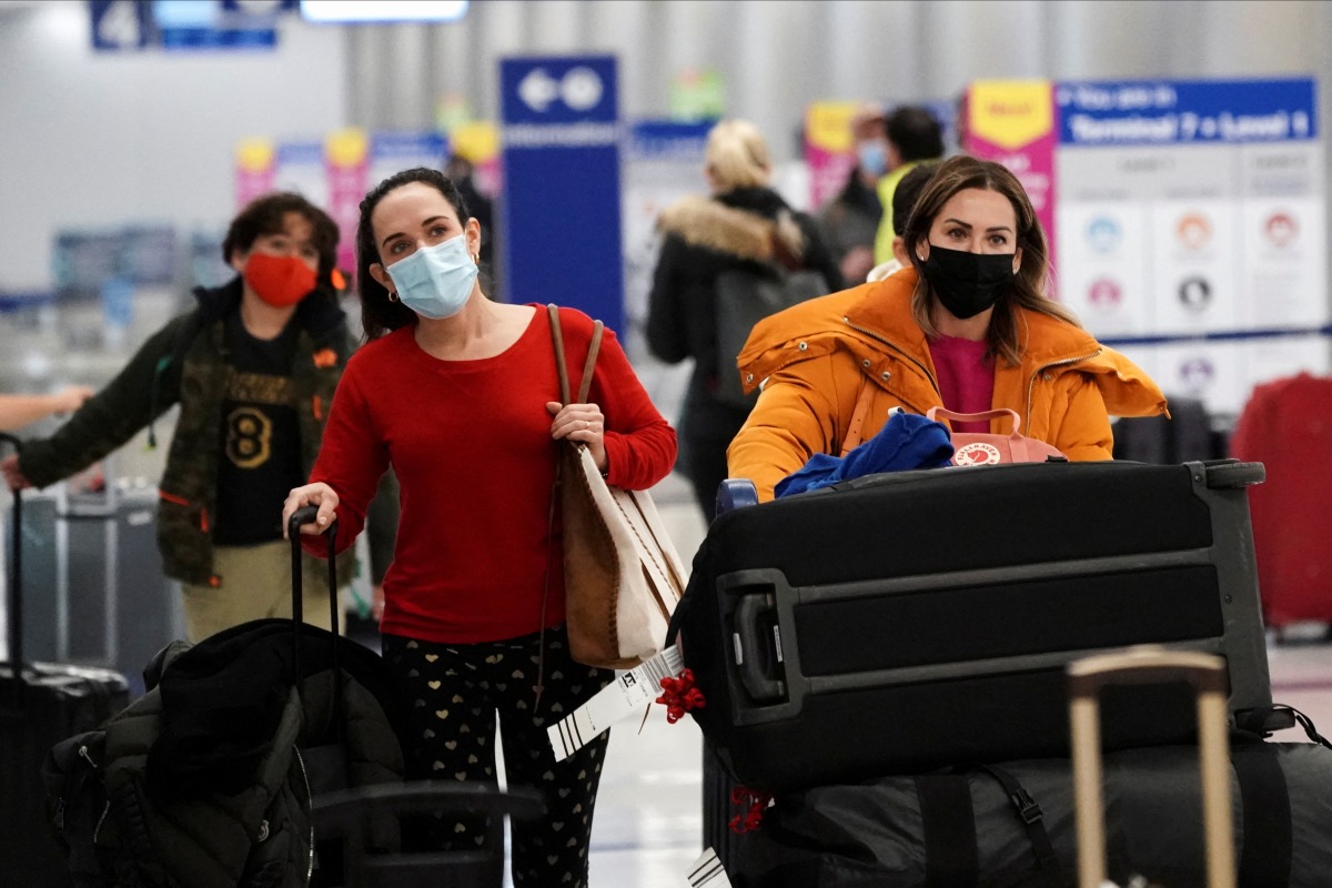 Travelers push their luggage past baggage claim inside the United Airlines terminal at Los Angeles International Airport (LAX) during the holiday season as the coronavirus disease (COVID-19) Omicron variant threatens to increase case numbers in Los Angeles, California, U.S. December 22, 2021. REUTERS/Bing Guan

