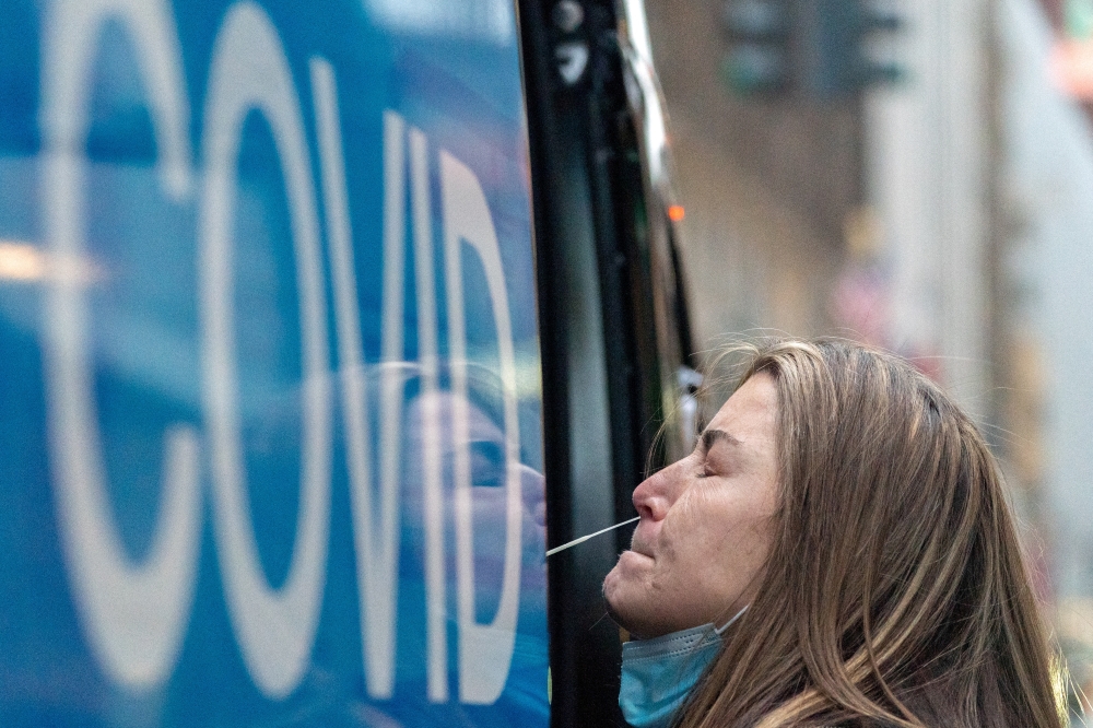 A woman takes a coronavirus disease (COVID-19) test at a pop-up testing site as the Omicron coronavirus variant continues to spread in Manhattan, New York City, U.S., December 27, 2021. Reuters/Jeenah Moon