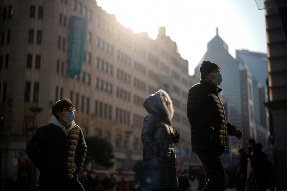 People wearing protective face masks walk on a street, following new cases of the coronavirus disease (COVID-19), in Shanghai, China, December 30, 2021. REUTERS/Aly Song