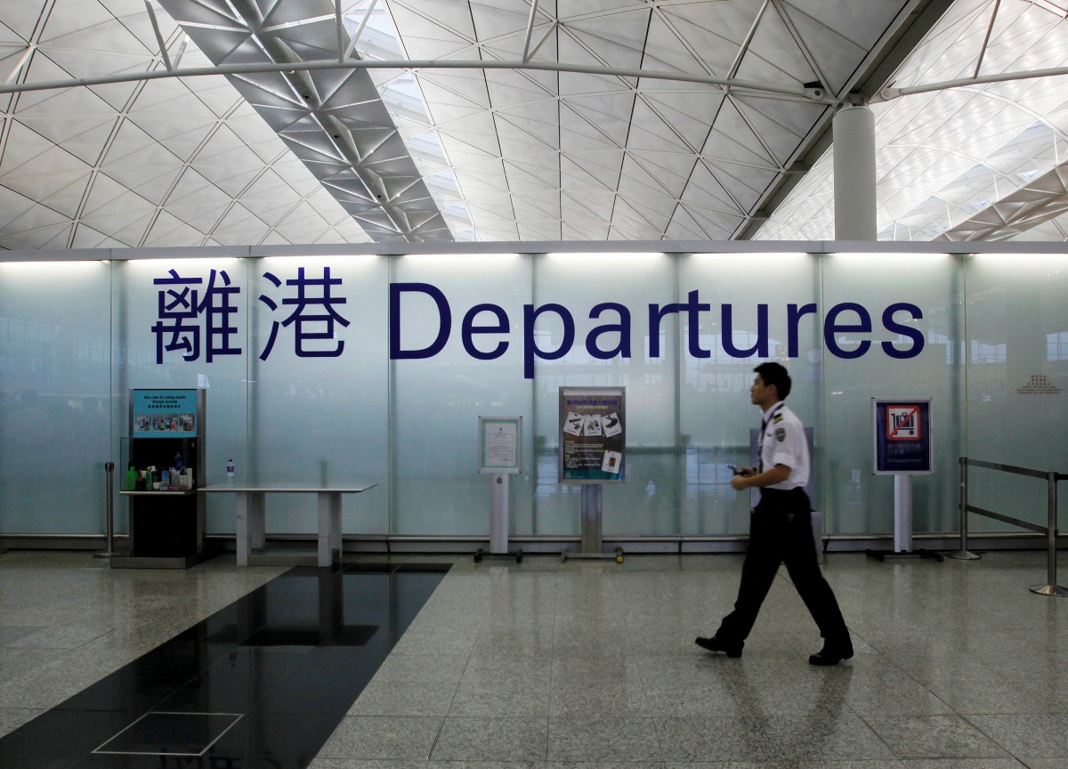 FILE PHOTO: An airport security guard walks past a sign at the departure hall of Hong Kong Airport June 23, 2013. REUTERS/Bobby Yip POLITICS)//File Photo
