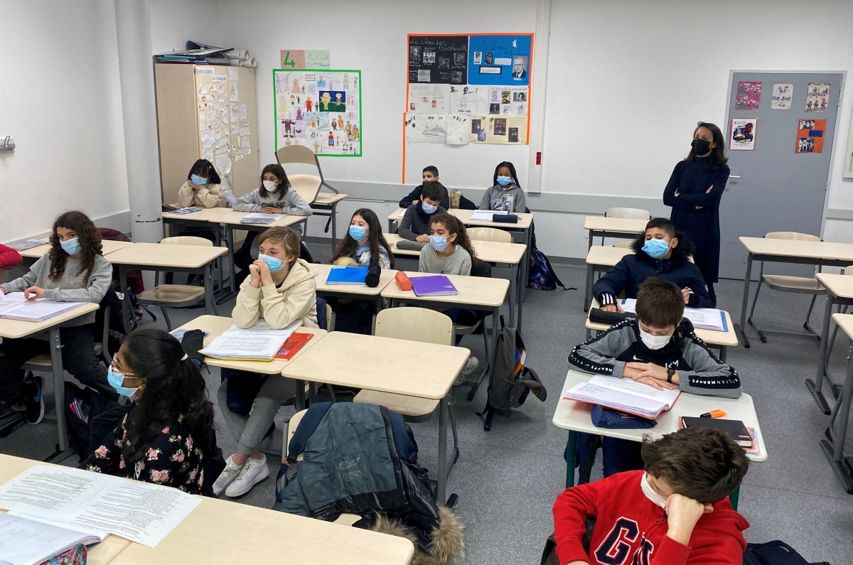 FILE PHOTO: Schoolchildren, wearing protective face masks, work in a classroom at the College Jean Renoir Middle School in Boulogne-Billancourt, near Paris, France, January 7, 2022. REUTERS/Yiming Woo/File Photo
