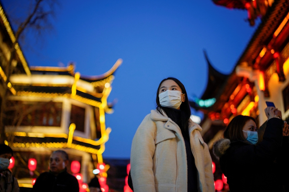 People wearing protective masks walk by an area decorated with lanterns ahead of the Chinese Lunar New Year festivity at Yu Garden, following new coronavirus disease (COVID-19) cases in Shanghai, China January 18, 2022. Reuters/Aly Song