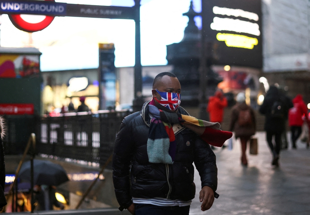 FILE PHOTO: A person wearing a protective face mask walks through Piccadilly Circus, amid the coronavirus disease (COVID-19) outbreak, in central London, Britain, January 6, 2022. REUTERS/Henry Nicholls