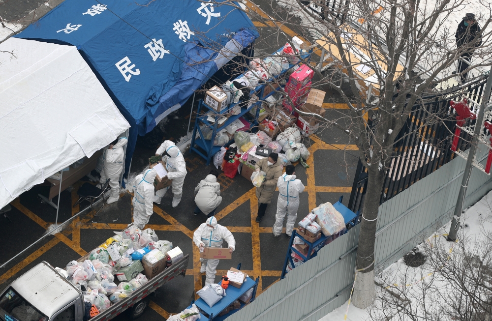 Workers in protective suits sort supplies to be delivered to residents at a compound under lockdown, in Fengtai district of Beijing, China January 23, 2022. cnsphoto via Reuters