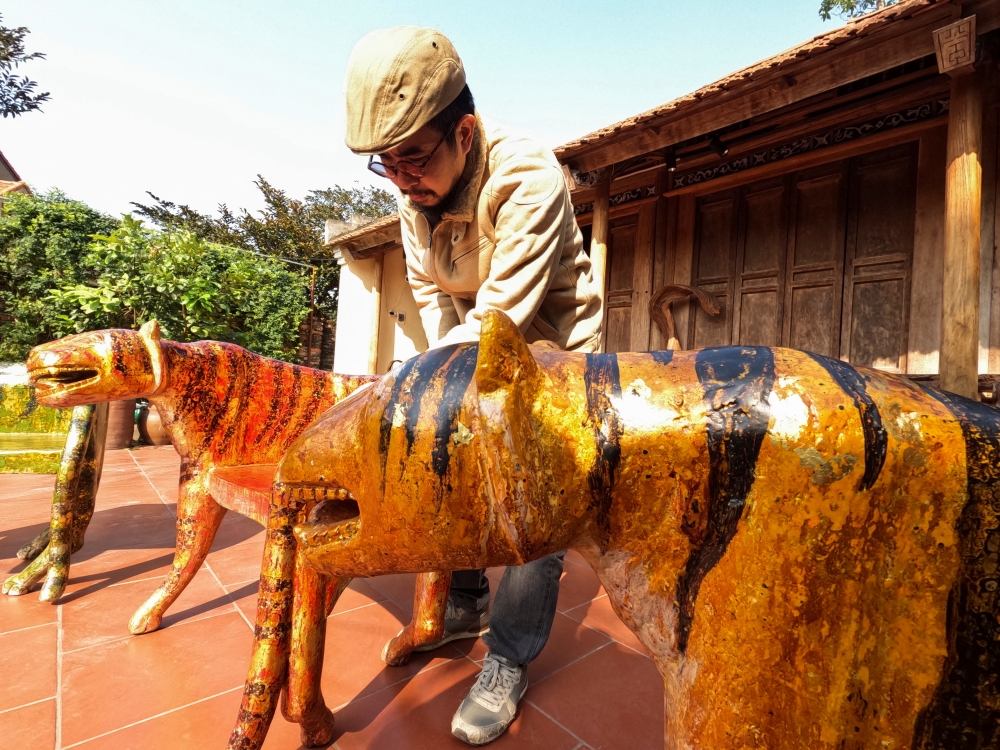 Nguyen Tan Phat stands in his yard with his Tiger carving works ahead of the Lunar New year in Hanoi, Vietnam January 18, 2022. Reuters/Stringer