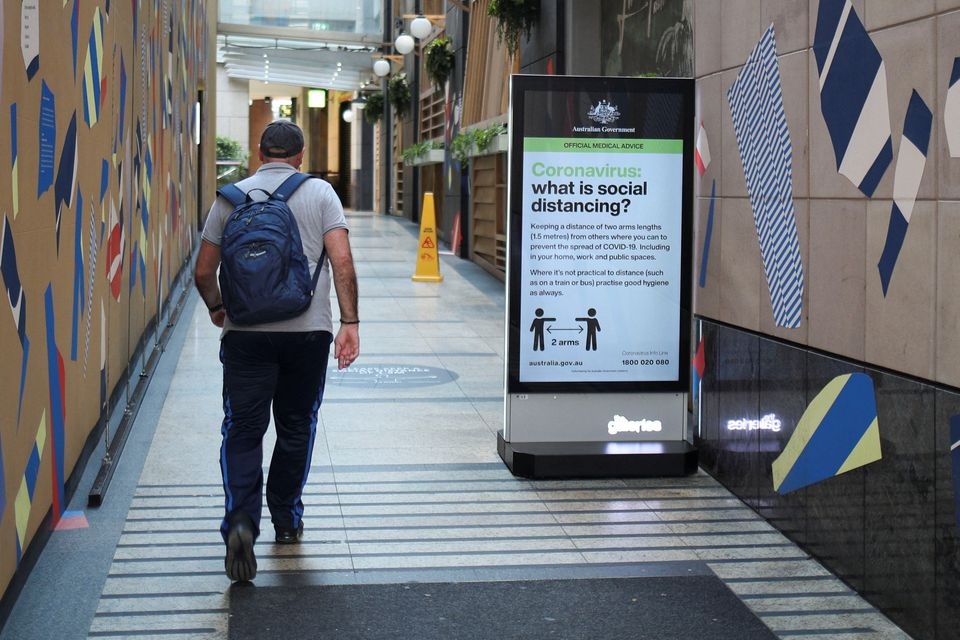A man walks in a corridor near a sign with instructions about the coronavirus and social distancing following the implementation of stricter social-distancing and self-isolation rules to limit the spread of the coronavirus disease (COVID-19) in Sydney, Australia, March 31, 2020. REUTERS/Loren Elliott

