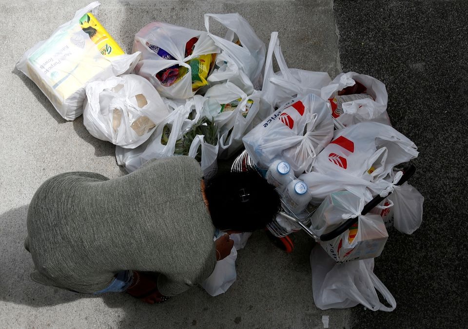 A woman packs her grocery shopping as she stocks up on food supplies, after Singapore raised coronavirus outbreak alert level to orange, outside a supermarket in Singapore February 8, 2020. REUTERS/Edgar Su/File Photo

