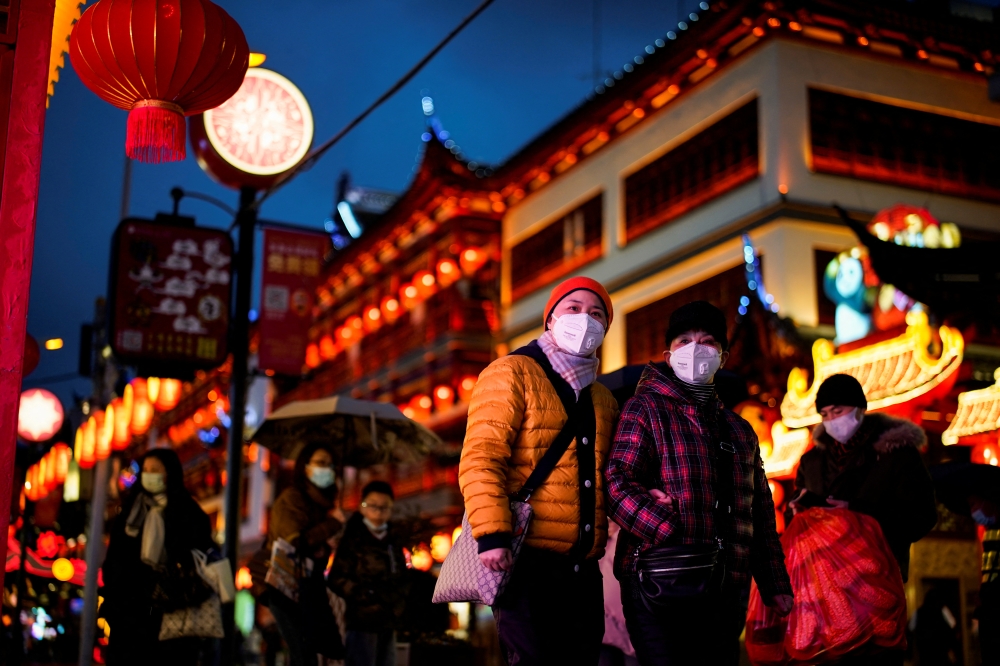 People wearing protective masks walk by an area decorated with lanterns ahead of the Chinese Lunar New Year festivity, following new coronavirus disease (COVID-19) cases in Shanghai, China January 28, 2022. REUTERS/Aly Song