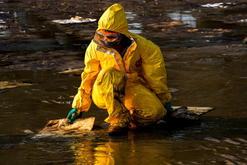 A worker cleans oil spills caused by a leak from an undersea pipeline 20 km (12.4 miles) off Thailand's eastern coast at Mae Ramphueng beach in Rayong province, Thailand, January 29, 2022. REUTERS/Athit Perawongmetha