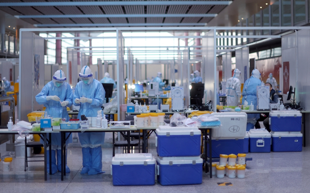 Staff members wearing personal protective equipment (PPE) designed to prevent the spread of the coronavirus disease (COVID-19), work at a COVID-19 testing site at Beijing Capital International Airport ahead of the Beijing 2022 Winter Olympics in Beijing, China, January 31, 2022.REUTERS/Hannah McKay