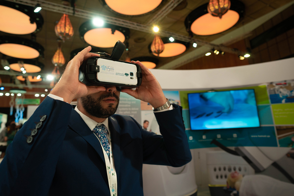 A summit delegate exploring a virtual reality (VR) device at the WISH 2018 Innovation Hub.