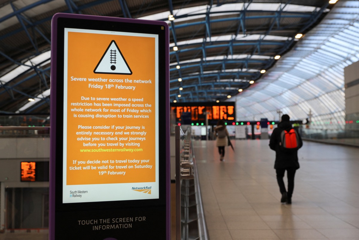 A person walks past a sign at Waterloo station, as a red weather warning was issued due to Storm Eunice, in London, Britain, February 18, 2022. REUTERS/May James
