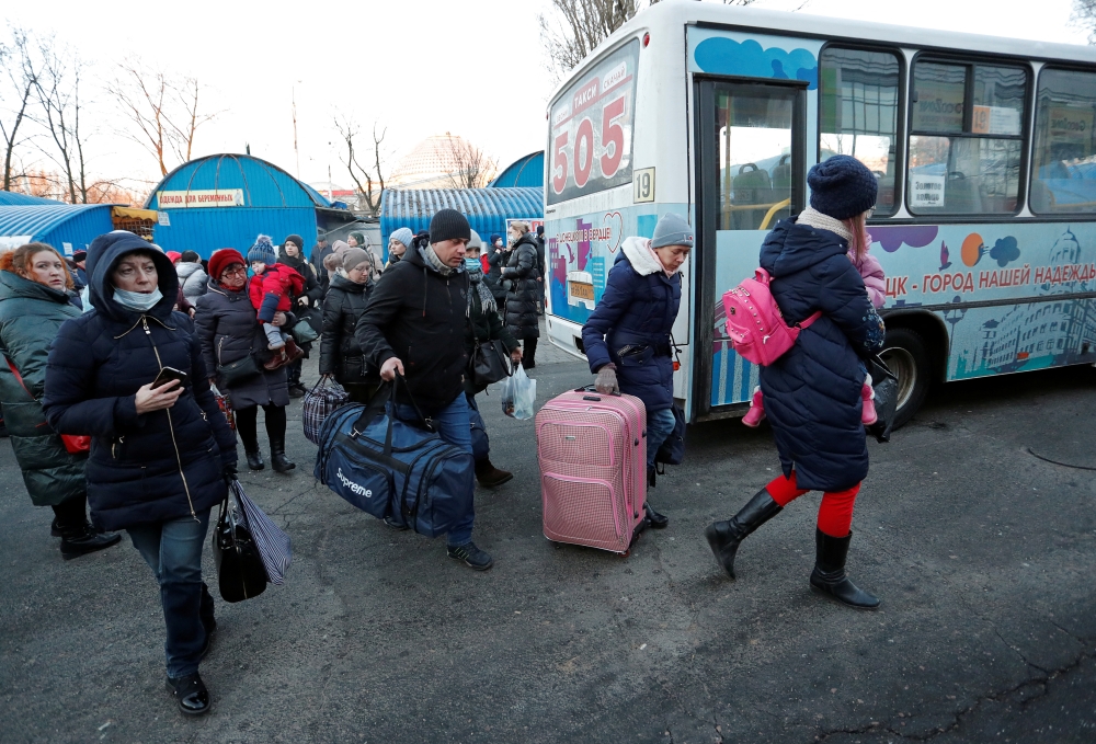 People walk to board a bus during the evacuation of local residents to Russia, in the rebel-controlled city of Donetsk, Ukraine February 19, 2022. Reuters/Alexander Ermochenko
 