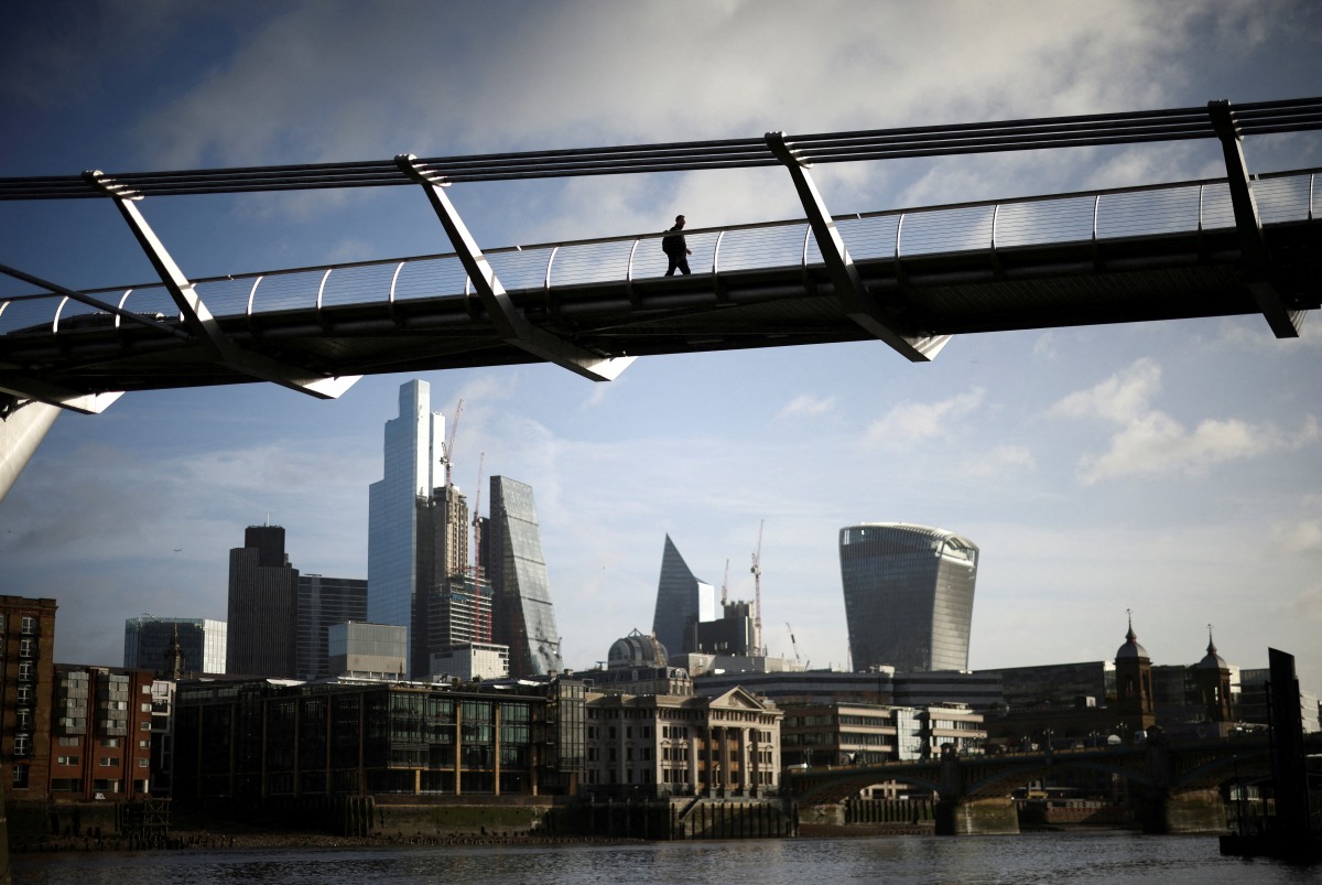 FILE PHOTO: The City of London financial district is seen as people walk over Millennium Bridge in London, Britain, February 16, 2022. REUTERS/Henry Nicholls/File Photo
