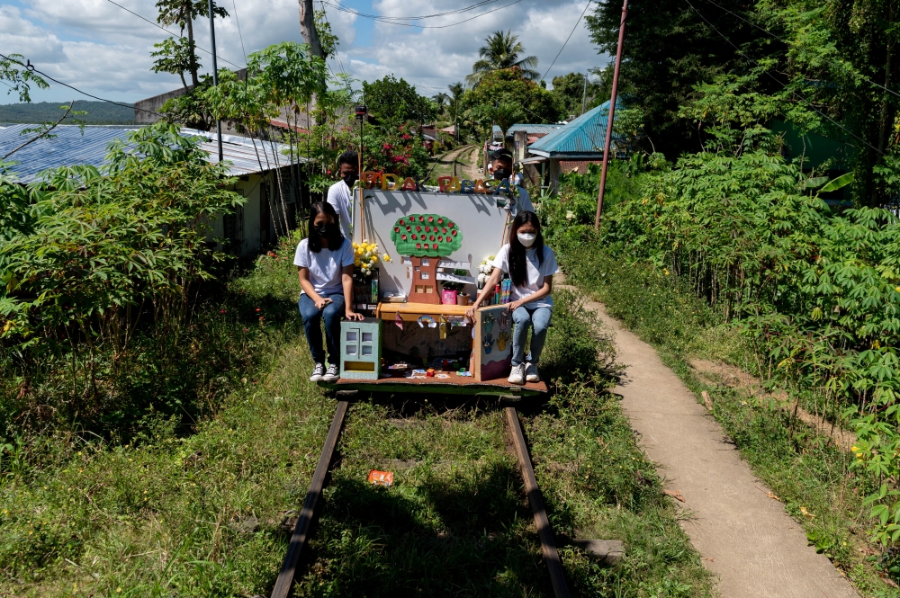 Student volunteers ride on their makeshift trolley which serves as a mobile library for children, in Tagkawayan, Quezon Province, Philippines, February 15, 2022. REUTERS/Lisa Marie David