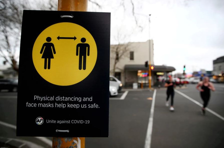 FPeople jog past a social distancing sign on the first day of New Zealand's new coronavirus disease (COVID-19) safety measure that mandates wearing of a mask on public transport, in Auckland, New Zealand, August 31, 2020. REUTERS/Fiona Goodall/File Photo

