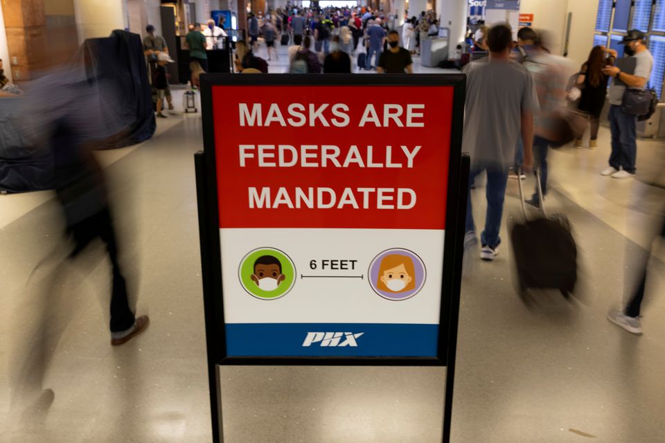 FILE PHOTO: Air travelers make their way past a sign mandating face masks for all during the outbreak of the coronavirus disease (COVID-19) at Phoenix international airport in Phoenix, Arizona, U.S. September 24, 2021. REUTERS/Mike Blake