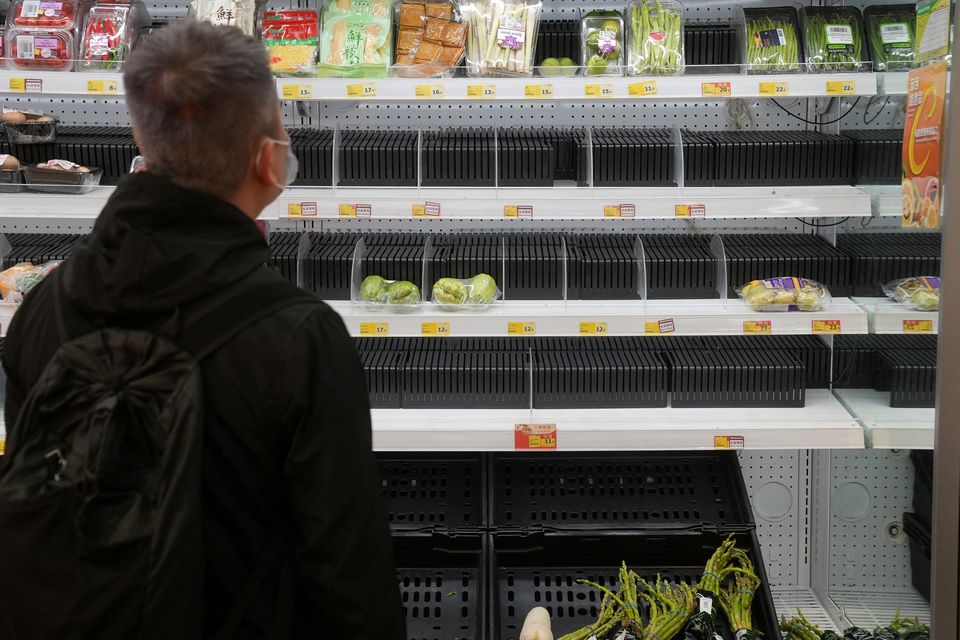 FILE PHOTO: A customer wearing a face mask shops in front of partially empty shelves at a supermarket, following the outbreak of the coronavirus disease (COVID-19), at Sha Tin district, in Hong Kong, China, February 7, 2022. REUTERS/Lam Yik
